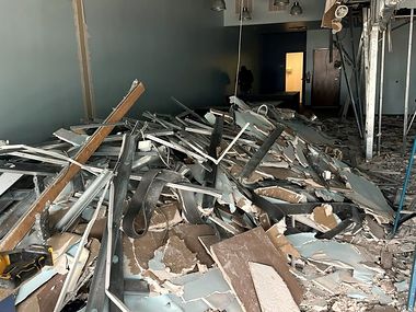 Before: a commercial interior filled with demolition debris — torn drywall, twisted metal studs, ceiling framing and insulation piled several feet deep across the floor.